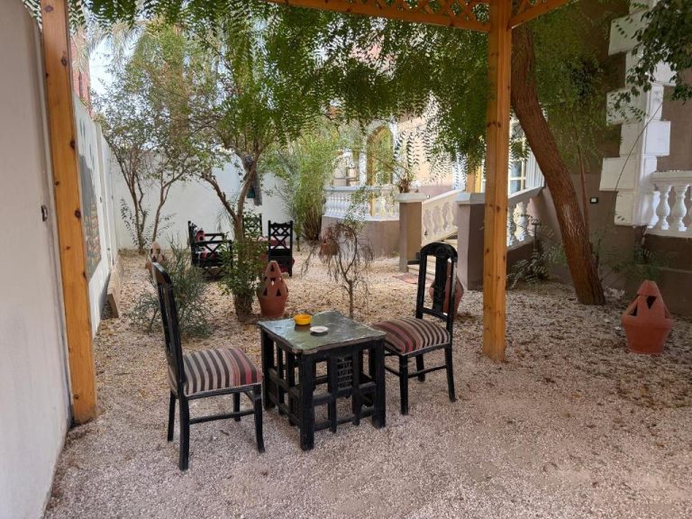 Jardín exterior con mesa y sillas de estilo árabe bajo pérgola de madera en Ramla Palace House