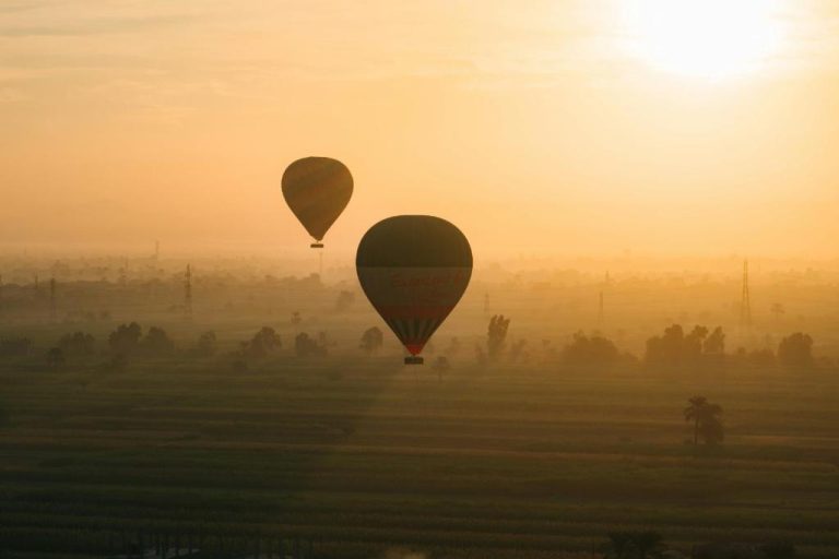 Vuelo en globos aerostáticos al amanecer sobre campos verdes cerca del Ramla Palace House