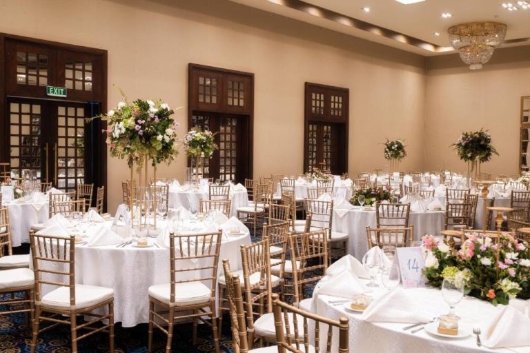 Elegante salón de banquetes para bodas con mesas redondas y arreglos florales en The Blue Water Geoffrey Bawa Heritage Resort