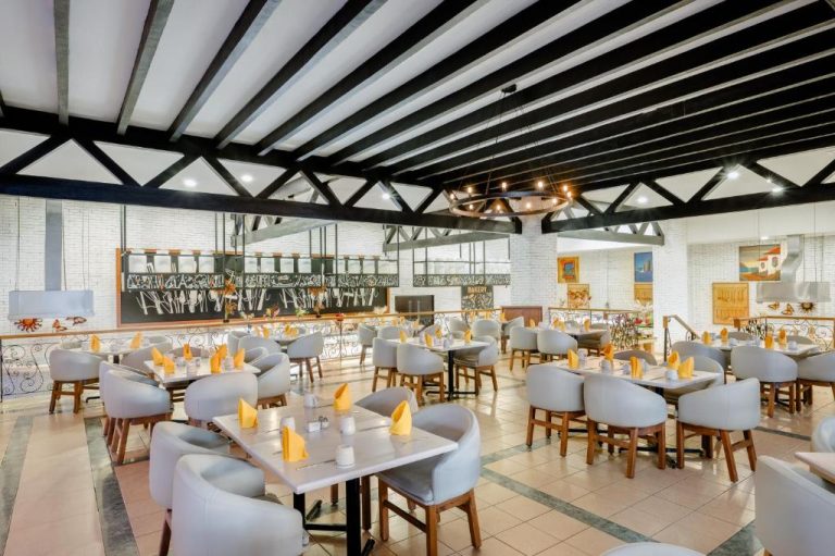 Amplio restaurante buffet con mesas y sillas blancas decoradas con servilletas amarillas en Royal Solaris Los Cabos