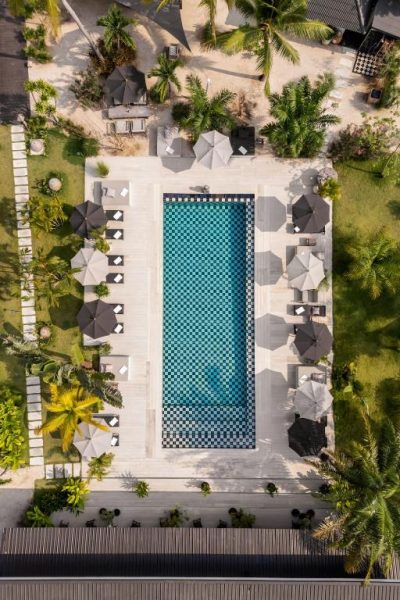 Vista aérea de la piscina exterior con patrón de tablero del Moorea Boutique Resort Samui rodeada de palmeras