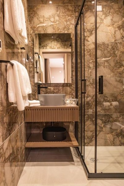 Baño de lujo con paredes de mármol y ducha acristalada en el Hotel Aquarius Dubrovnik