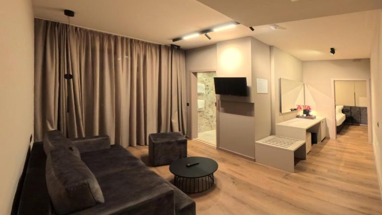 Suite con salón moderno, sofá gris y televisión en el Hotel Aquarius Dubrovnik