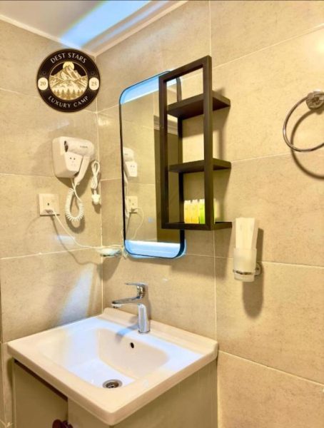 Baño moderno con lavabo, espejo iluminado y secador de pelo en Dest Stars Luxury Camp