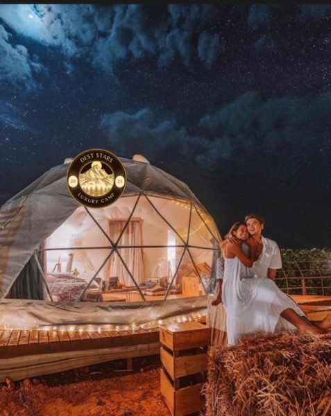 Pareja romántica en domo glamping iluminado bajo cielo estrellado en Dest Stars Luxury Camp