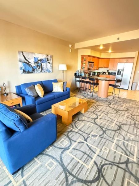 Salón con sofás azules y cocina americana equipada en Idyllic Suite Las Vegas
