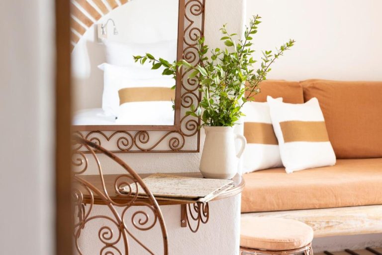 Detalle decorativo con espejo forjado y plantas naturales en habitación del hotel U Capu Biancu