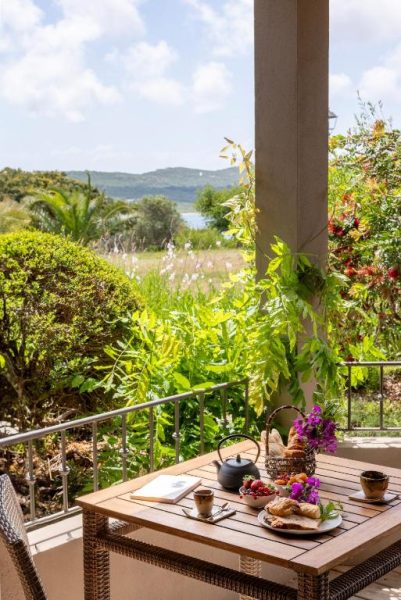 Terraza con desayuno y vistas al jardín y mar en el Hotel U Capu Biancu en Córcega