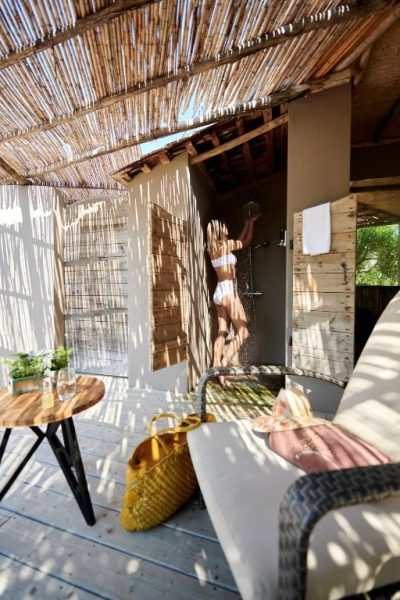 Ducha exterior de diseño rústico con terraza de madera y techo de bambú en el hotel U Capu Biancu