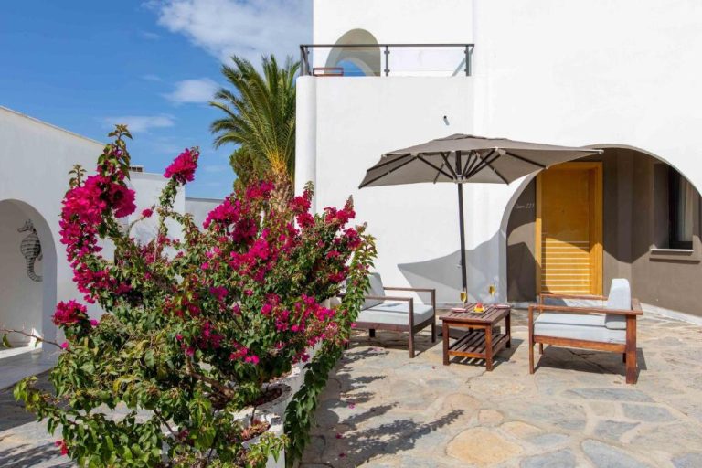 Terraza con bugambilias rosas y sombrilla en Senses Hotel Adults Only con arquitectura blanca mediterránea