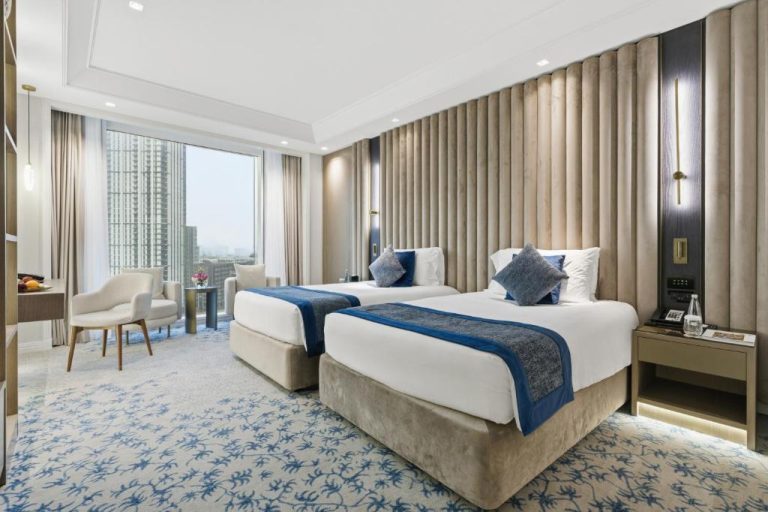 Habitación twin de lujo con vistas a la ciudad y decoración elegante en azul y beige en el Taj Dubai