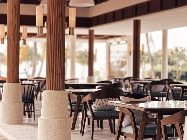 Restaurante terraza abierta con mesas y sillas de madera en el resort RAH GILI Maldives
