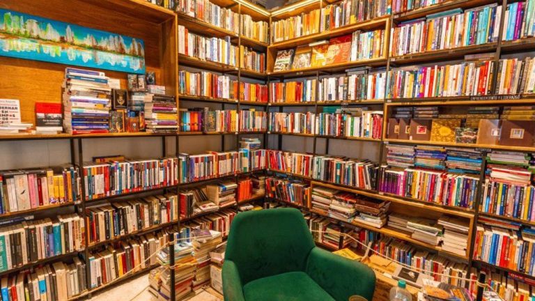 Rincón de lectura con sillón verde y estanterías llenas de libros en Hotel Libreria Cafe de Pombal