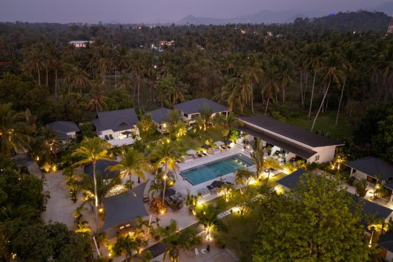 Vista aérea nocturna de la piscina exterior y jardines tropicales del Moorea Boutique Resort Samui