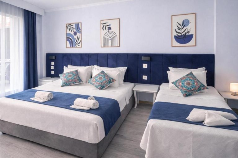 Habitación triple con dos camas y decoración en azul y blanco en el Akman City Hotel