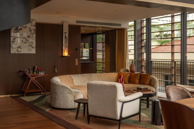 Elegante sala de estar con sofá curvo y sillones en el Rosewood São Paulo con vistas al exterior