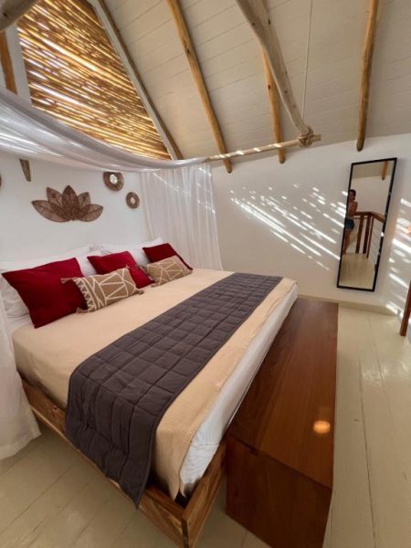 Habitación con cama doble, almohadas rojas y techo de bambú natural en Leeloo Boutique Hotel