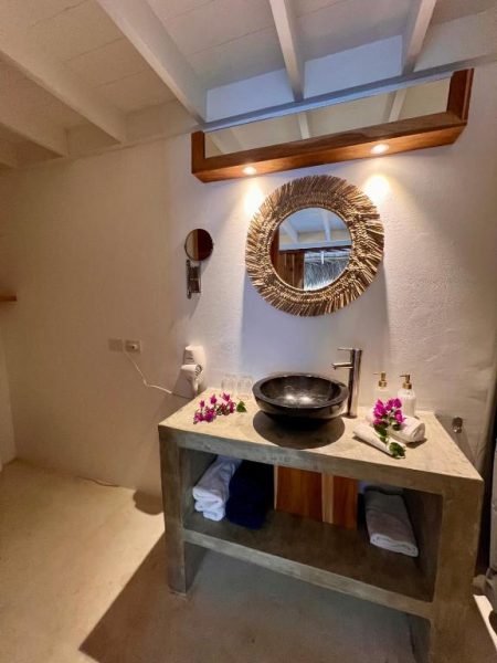 Baño elegante con lavabo de piedra y espejo dorado decorativo en Leeloo Boutique Hotel