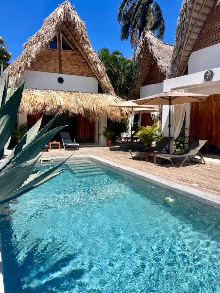 Piscina exterior con tumbonas y palapa de paja del Leeloo Boutique Hotel en ambiente tropical
