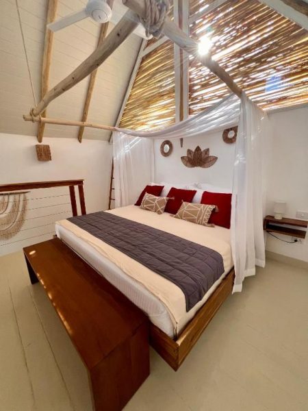 Habitación con cama dosel y techo de paja estilo boho en Leeloo Boutique Hotel