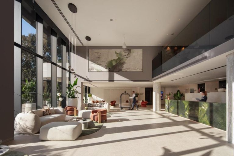 Amplio lobby moderno con zona de descanso y recepción en mármol verde del Hotel Sumratin