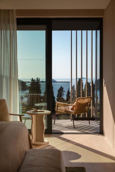 Terraza con silla de ratán y vistas al mar en el Hotel Sumratin con vegetación mediterránea