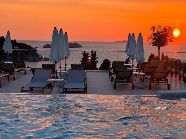 Piscina infinita con tumbonas y vistas al mar al atardecer en el Hotel Sumratin