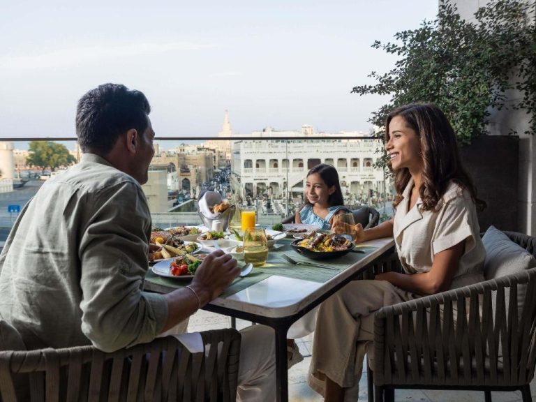 Familia disfrutando de una cena en la terraza del Alwadi Hotel Doha MGallery con vistas al casco antiguo