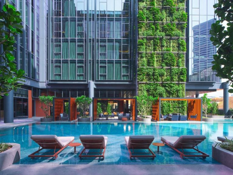Piscina exterior con tumbonas y jardín vertical del Pullman Singapore Hill Street
