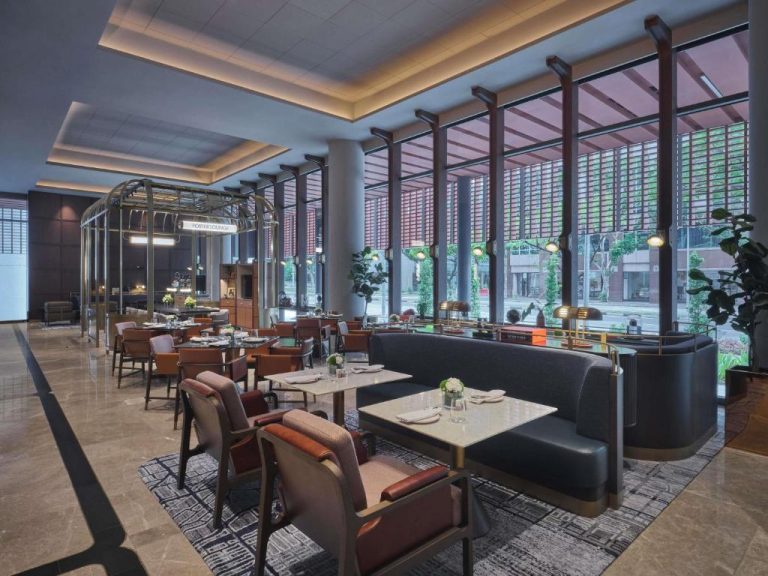 Elegante restaurante Porter Lounge del Pullman Singapore Hill Street con sofás y mesas junto a ventanales