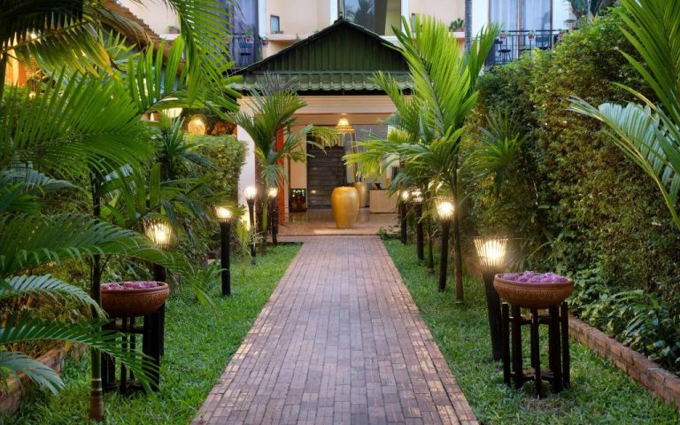 Jardín tropical con camino de ladrillos iluminado que conduce a la entrada del Central Boutique Hotel