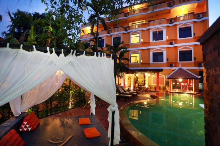 Piscina exterior iluminada con cabana de lujo y tumbonas del Central Boutique Hotel al atardecer