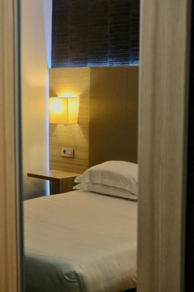 Habitación individual con cama blanca e iluminación cálida en Hôtel L'Escale Côté Port
