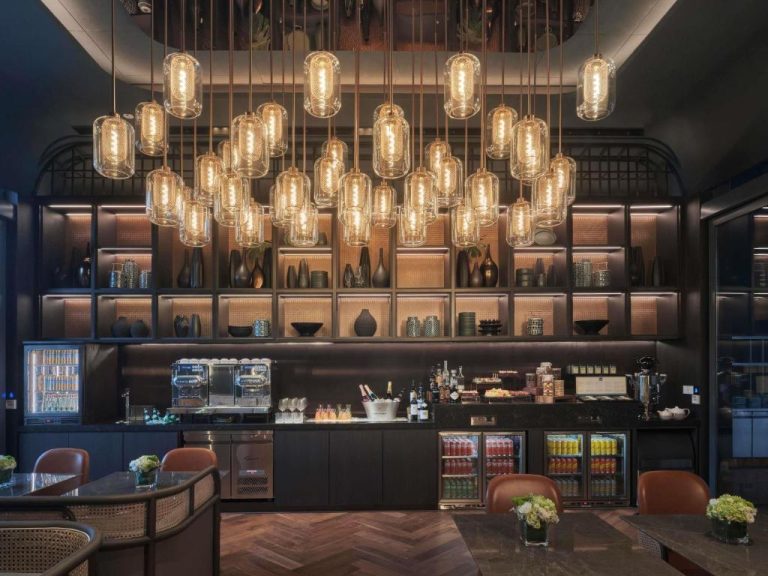 Bar lounge elegante con lámparas colgantes del Pullman Singapore Hill Street y estantes decorativos