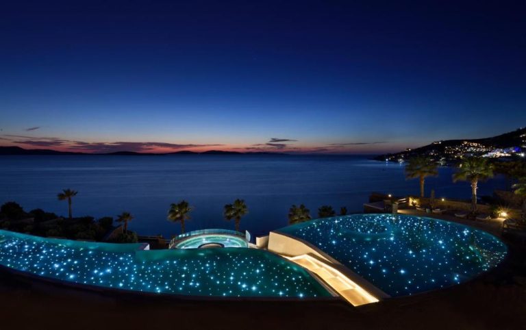 Piscina infinita iluminada con luces estrelladas del Anax Resort and Spa con vistas al mar al atardecer