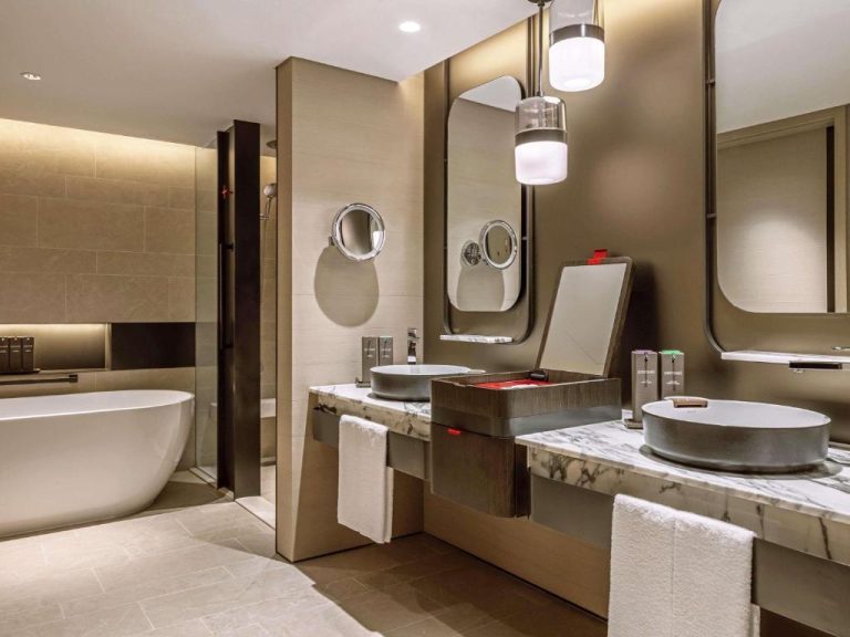 Baño de lujo con bañera exenta y doble lavabo de mármol en Swissotel The Stamford Singapore