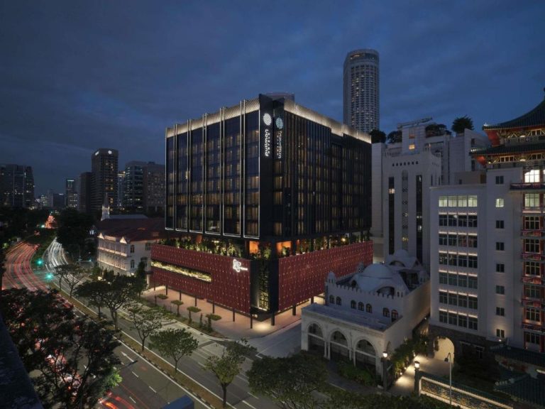 Vista nocturna del Pullman Singapore Hill Street con su fachada moderna iluminada y mezquita histórica adyacente