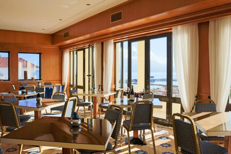 Restaurante con mesas elegantes y vistas panorámicas al mar en el Hotel Horta