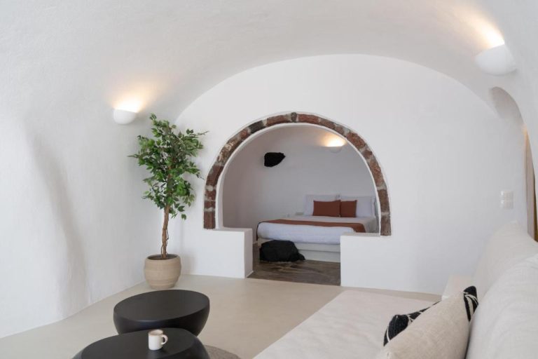 Habitación cueva con arco de piedra y cama integrada en You and Me Suites Oia, Santorini