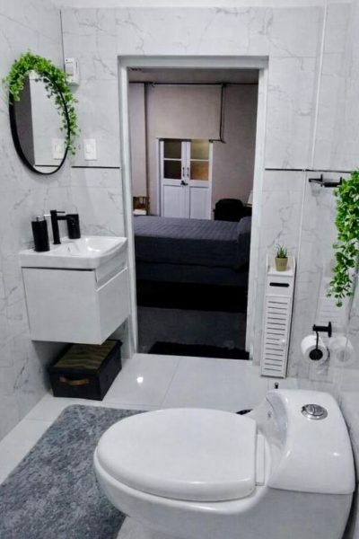 Baño moderno con revestimiento de mármol blanco y vista a dormitorio en habitación con balcón ciudad