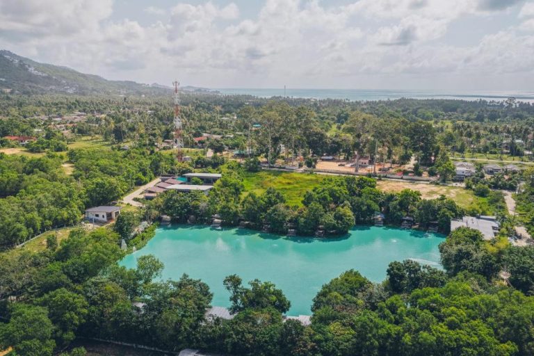 Vista aérea del lago turquesa rodeado de vegetación tropical en Samui Fishing Club and Resort, Koh Samui