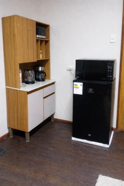 Rincón de cocina con minibar Electrolux, microondas LG y cafetera en habitación con vista a la ciudad