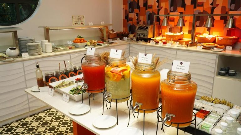 Estación de zumos naturales de naranja y mango en el buffet de desayuno del Hennessy Park Hotel