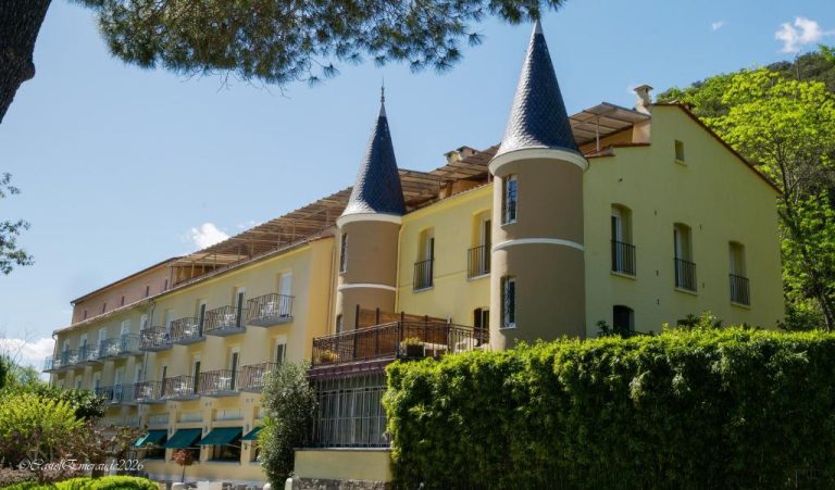 Fachada exterior del Appart'Hotel Castel Emeraude con torres puntiagudas y balcones entre vegetación