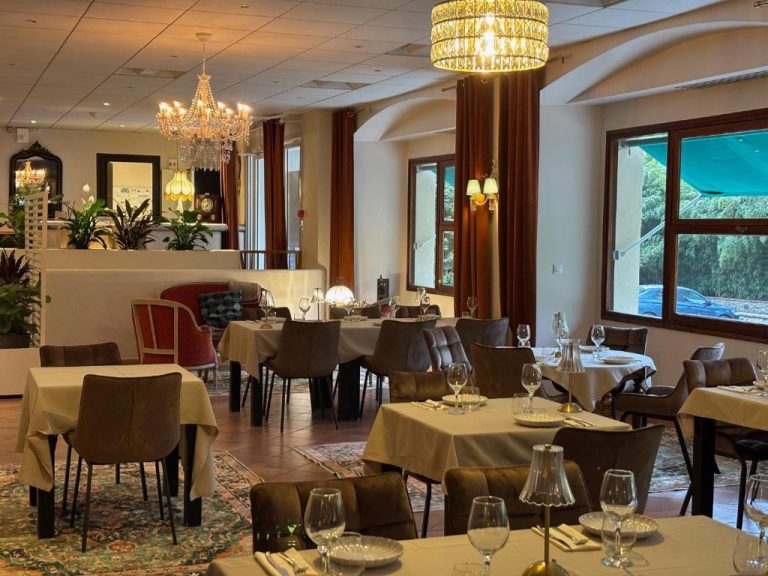 Elegante salón comedor del Appart'Hotel Castel Emeraude con mesas vestidas y lámparas de araña