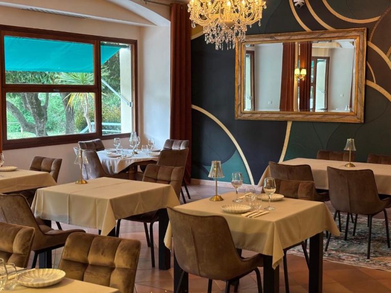 Elegante salón comedor del Appart'Hotel Castel Emeraude con mesas vestidas y lámpara de araña