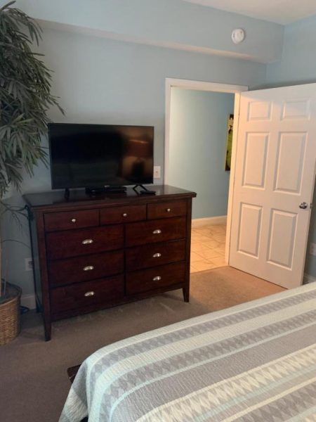 Habitación con cama king, cómoda de madera oscura y televisor en 1717 Laketown Wharf