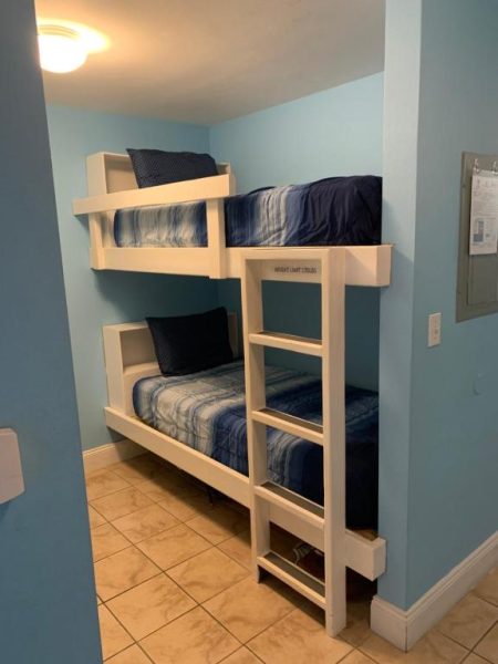 Habitación con literas dobles blancas y ropa de cama azul en el apartamento 1717 Laketown Wharf