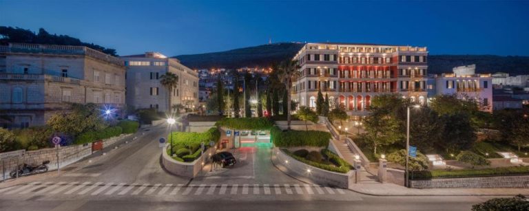 Vista nocturna de la fachada exterior iluminada del Hilton Imperial Dubrovnik con jardines