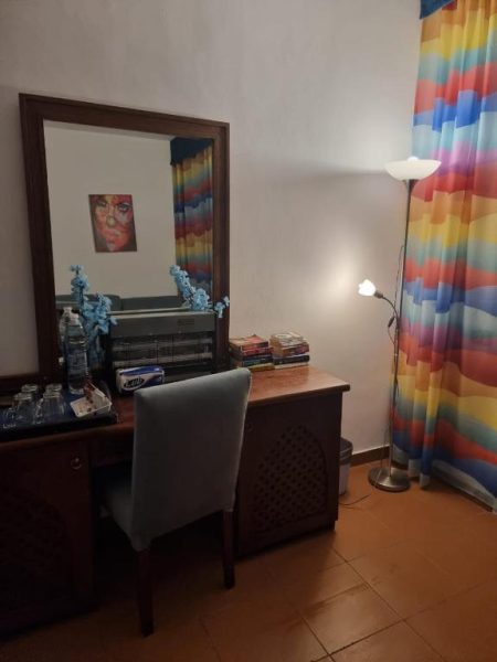 Escritorio con espejo, silla y lámpara en estudio del Domina Coral Bay con cortinas de colores